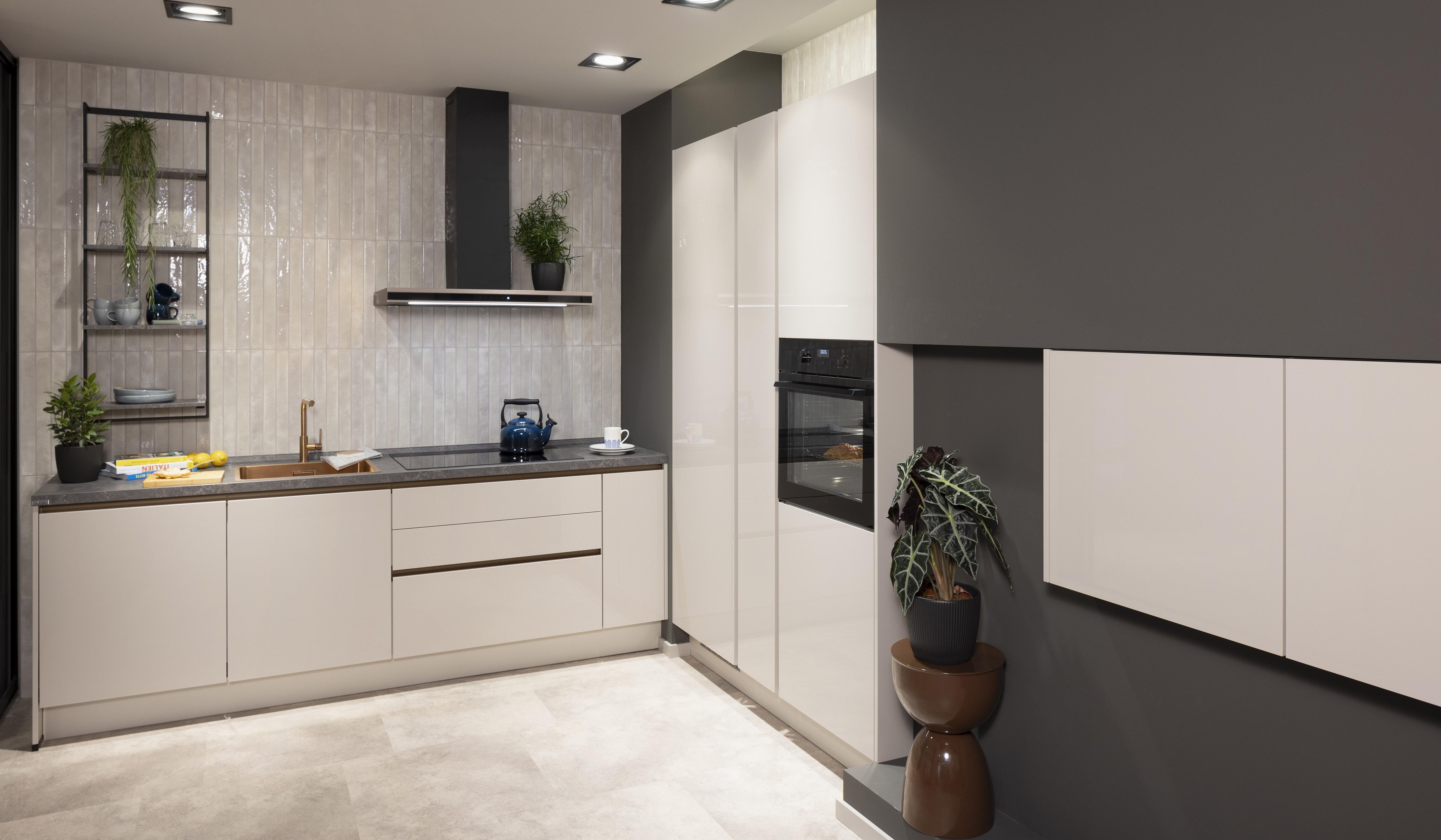Moderne Küche mit weißen Schränken, grauer Wand und eingebautem Backofen.