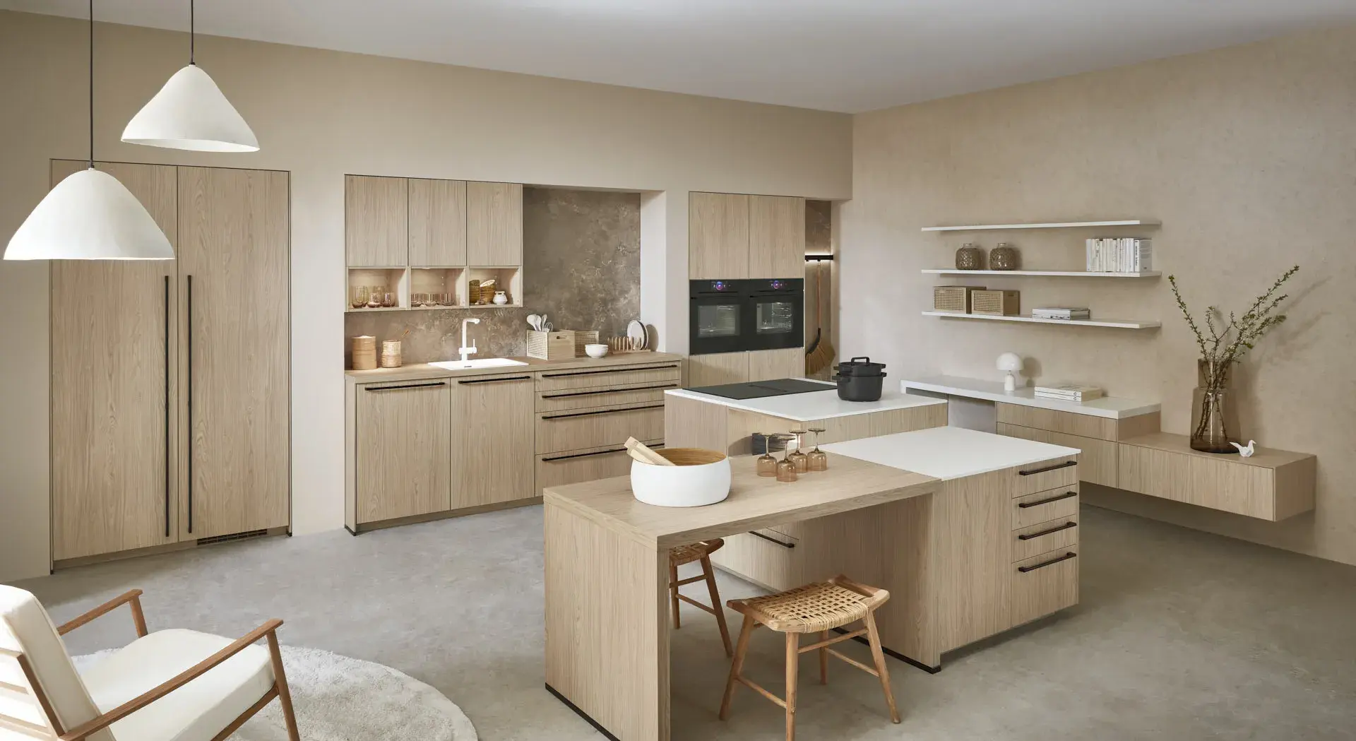 Gegenschuss, Mix aus Eichennachbildung und Premium Matt weiß, 2 Kücheninseln, eine mit Bosch Induktionskochfeld und Muldenlüfter, 2 Bosch Einbaubacköfen, Sitzbereich, 3 Oberschränke über der Spüle, Regalelement an der Wand, graue Nischenrückwand